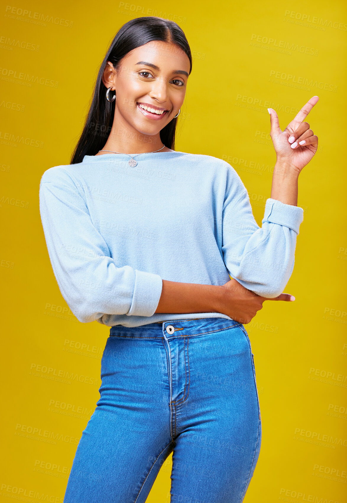 Buy stock photo Pointing, mockup and portrait of a woman in a studio for advertising, marketing or promotion. Smile, happy and young Indian female model with a direction hand gesture isolated by yellow background.