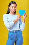 Portrait, smile and woman with blue heart in studio with help, hope or empathy on yellow background. Face, lady and social media poster for thank you or support for autism or people with a disability