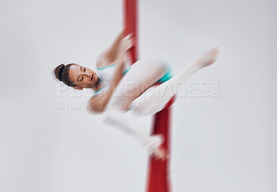 Gymnastics, woman and aerial silk with a acrobat in air for performance, sports and balance. Young athlete person or gymnast hanging on red fabric and white background with space, art and creativity