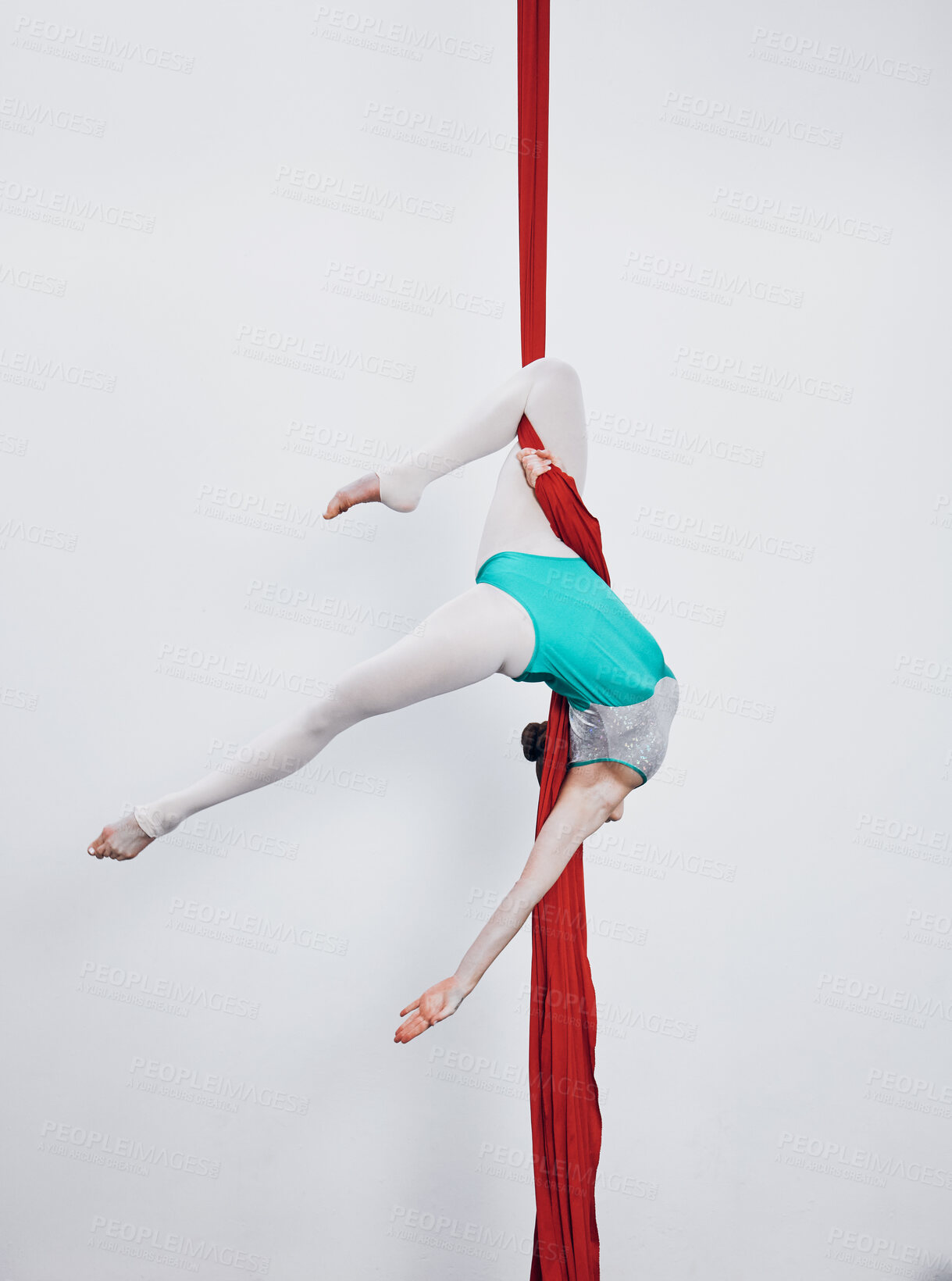 Buy stock photo Aerial silk, acrobat and gymnastics with a woman in air for performance, sports and balance. Young athlete person or gymnast hanging on red fabric and white background with space, art and creativity