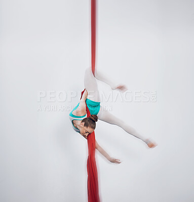 Gymnastics, acrobat and aerial silk with a sports woman in air for performance and balance. Young athlete person or gymnast hanging on red fabric and white background with space, art and creativity