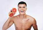 Beauty, grapefruit and smile with portrait of man in studio for skincare, detox and natural cosmetics. Vitamin c, nutrition and spa with person and fruit on white background for self care and glow 