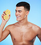 Beauty, smile and skincare with man and lemon in studio for health, detox and natural cosmetics. Vitamin c, nutrition and summer with person and fruit on blue background for self care, spa and glow 