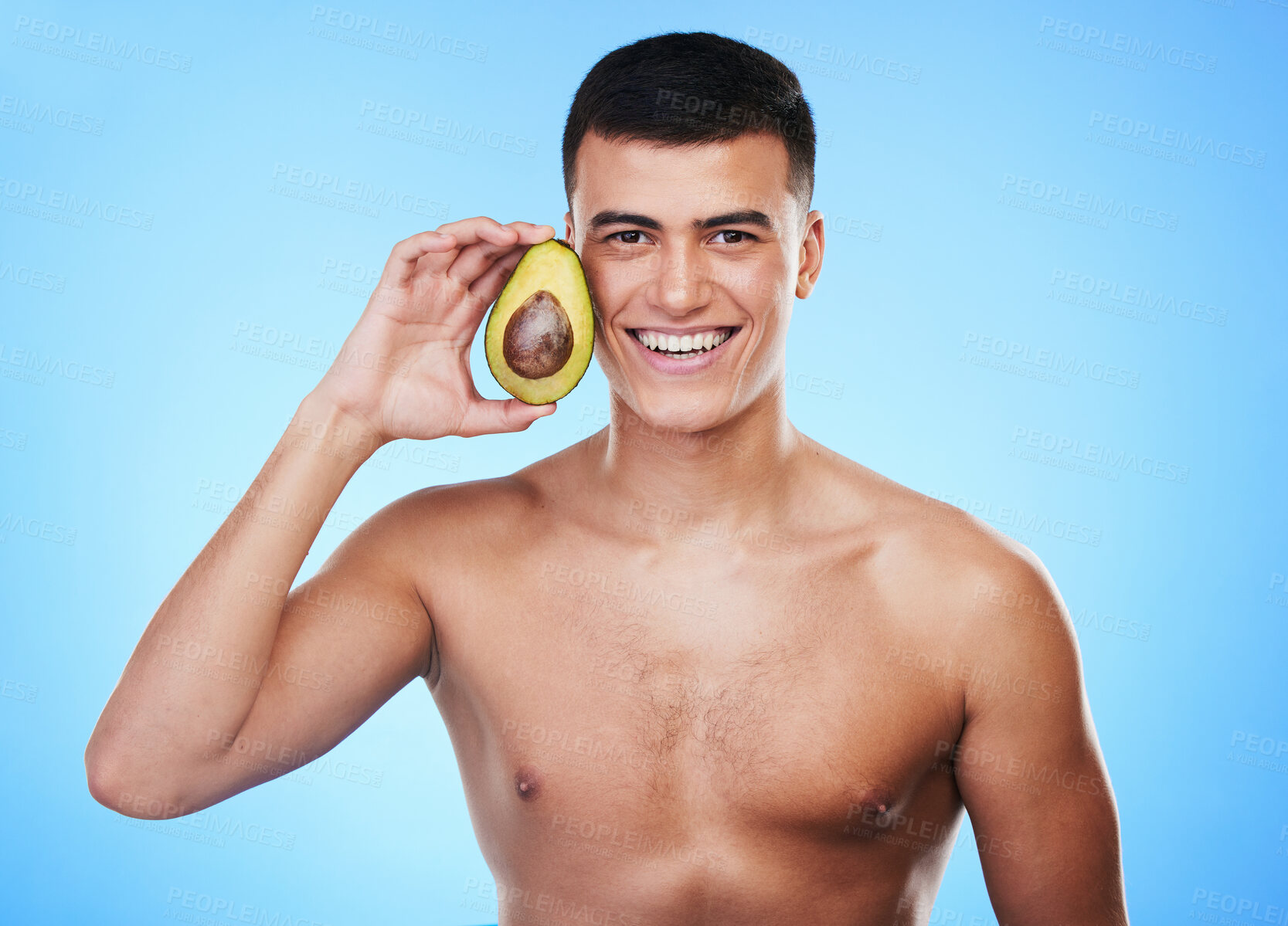 Buy stock photo Avocado, wellness and portrait with skincare and natural facial treatment in studio. Blue background, health food and cosmetics with male model holding fruit for nutrition for face and beauty glow