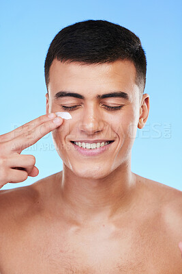 Buy stock photo Skincare, beauty and man in a studio with face cream for a health, wellness and self care routine. Cosmetic, dermatology and young male model with facial spf, lotion or sunscreen by a blue background