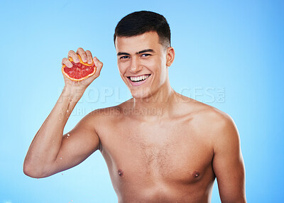 Buy stock photo Smile, grapefruit and squeeze with portrait of man in studio for health, detox or natural cosmetics. Vitamin c, nutrition and skincare with person and fruit on blue background for self care and glow 