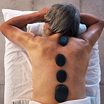 Hot stone massage and back of man in spa for wellness, holistic treatment and hospitality. Peace, cosmetics and beauty salon with body of customer at hotel for relax, vacation and physical therapy