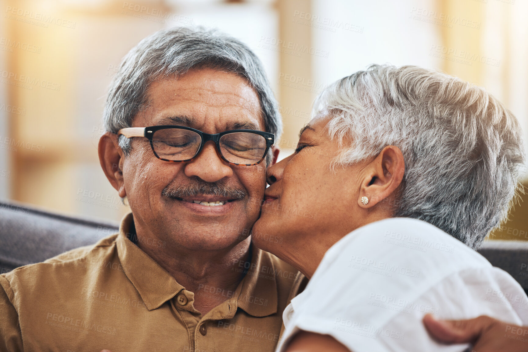 Buy stock photo Love, kiss and senior couple on sofa for bonding, healthy marriage and relationship in living room. Retirement, relax and happy man and woman on couch embrace for trust, commitment and care at home