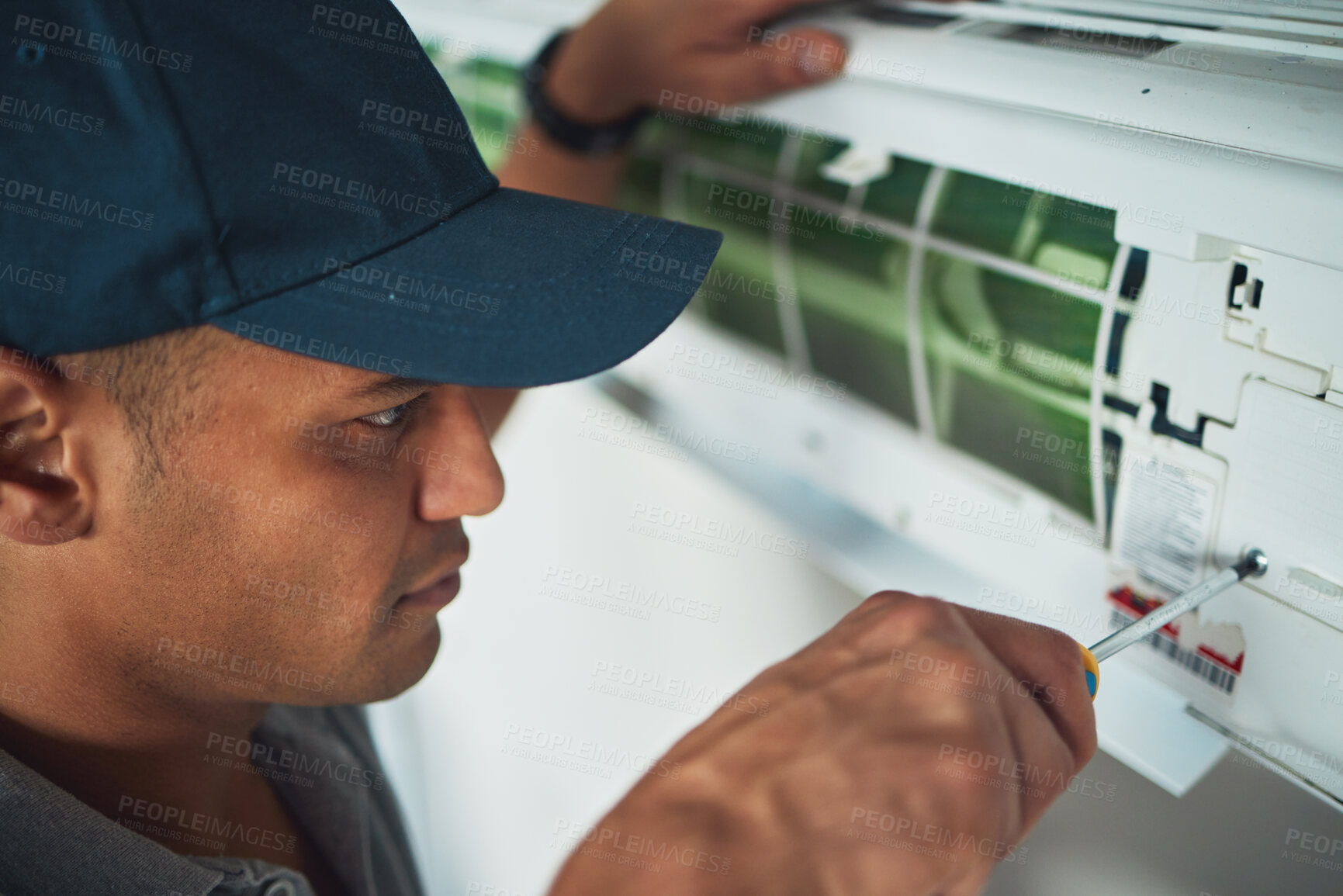 Buy stock photo Face, hand and a man for aircon repair or maintenance in an office for circulation or central heating. Construction, tools or screwdriver with an engineer working on an air conditioning unit closeup