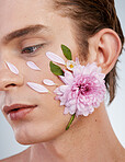 Natural, skincare and flowers on face of man in studio for spring, beauty cosmetics and creative. Glow, self love and floral with model on white background for makeup, spa treatment and wellness