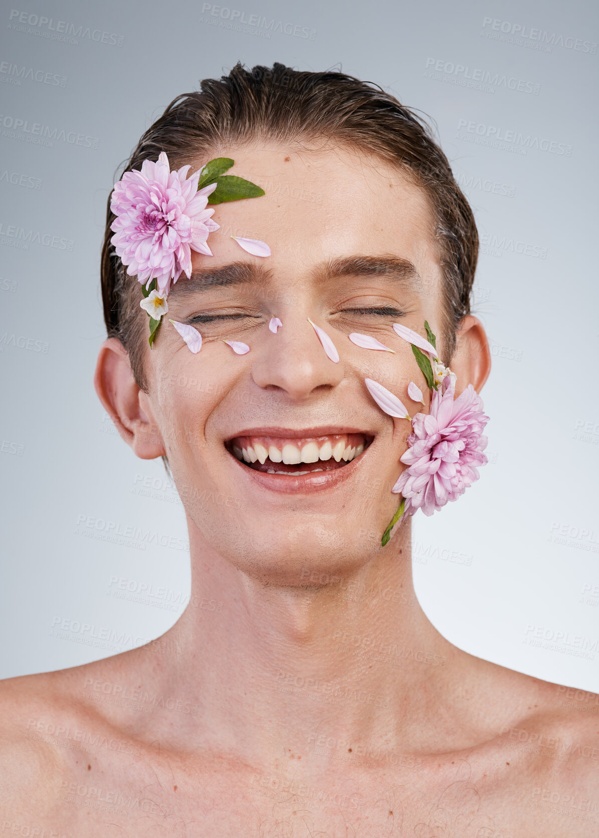 Buy stock photo Happy, skincare and flowers on face of man in studio for spring, natural cosmetics and creative. Glow, self love and floral beauty with model on white background for makeup, spa treatment or wellness