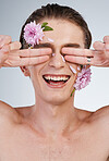 Beauty, funny and flowers on face of man in studio for spring, natural cosmetics and creative. Glow, self love and floral with model on white background for makeup, spa treatment and wellness