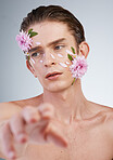 Touch, skincare and flowers on face of man in studio for spring, natural cosmetics and creative. Glow, self love and floral with model on white background for makeup, spa treatment and wellness