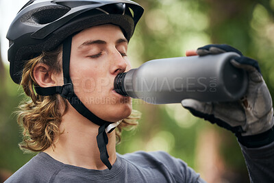Buy stock photo Forest, biker and man with a water bottle, wellness and exercise with workout, refreshing and break. Healthy person, athlete or guy in the woods, hydration and outdoor with liquid, fitness and helmet