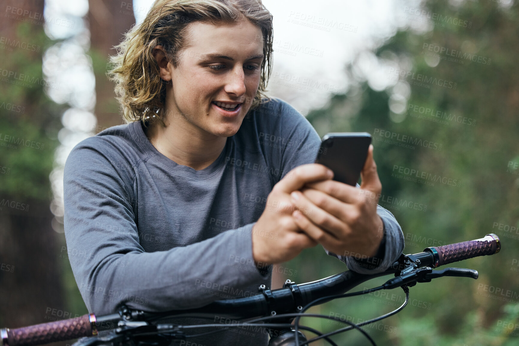 Buy stock photo Phone, bicycle and man in forest, smile and social media, internet or sport training. Smartphone, bike and happy person in woods, cycling for healthy body on app and eco friendly transport to travel