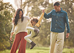 Holding hands, park and parents playing with girl in nature for fun, bonding and relax together. Happy family, childhood and mother, father and child jump outdoors on holiday, adventure and vacation