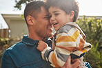 Outdoor, father and boy with a smile, hug and sunshine with fun, playful and bonding in a backyard. Parent, kid and dad with child, garden and sunlight with freedom, weekend break and summer with joy