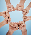 People, hands together and fist bump in teamwork, unity or community below blue sky background. Low angle, closeup or group goals in team building, motivation or support in trust on mockup space