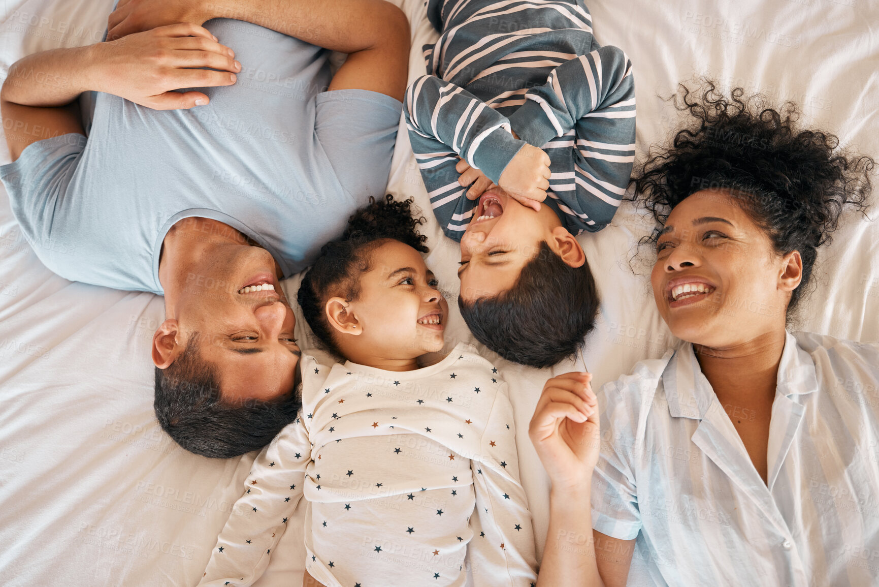 Buy stock photo Happy, funny and relax with family in bedroom for playful, morning and love. Care, support and wake up with parents and children from above in bed at home for weekend, positive or smile together