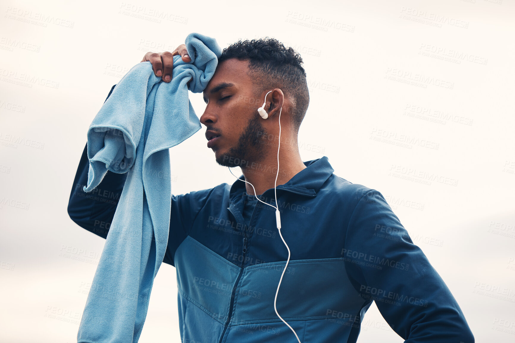 Buy stock photo Tired runner man, outdoor and towel with earphones, music and cleaning for sweat, hygiene and wellness in morning. Guy, thinking and training for marathon with fatigue, cloth and burnout in nature