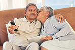 Kiss, TV and senior couple streaming movie or show with love, care and bonding in home living room together. Tablet, remote and elderly people relax and watching a subscription service on retirement