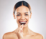 Woman, eating chocolate and portrait for skincare, beauty and wellness, health or diet on white background. Young person or face of model with cacao or candy for skin care and dermatology in studio