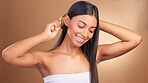 Beauty, smile and Indian woman with hair brush in studio for shampoo, results or scalp wellness on brown background. Haircare, texture and lady model happy with growth, keratin or volume satisfaction