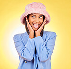 Fashion, tongue and face of Indian woman on yellow background with silly, goofy and playful expression. Emoji, happiness and person in studio with comic pose in trendy accessories, style and hat