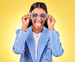 Funny, woman smile and sunglasses with tongue out, comedy and silly face in a studio. Yellow background, crazy and female person with modern fashion, trendy cool style and creative work clothing