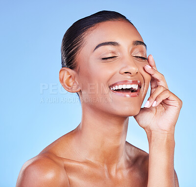 Buy stock photo Skincare, beauty and hand on face with happy woman in studio with blue background and dermatology or cosmetics. Indian, model and happiness with natural skin and healthy glow from facial or self care