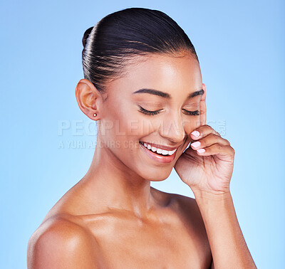 Buy stock photo Beauty, skincare and hand on face with happy woman in studio with blue background and dermatology or cosmetics. Indian, model and happiness with natural skin and healthy glow from facial or self care