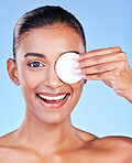 Portrait, woman and cotton pad on eyes for healthy skincare, cosmetics or smile on blue background in studio. Face of happy indian model, facial cleaning or beauty of dermatology, glow or wipe makeup