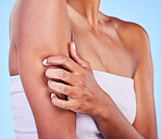 Arm injury, stress and hands of woman in studio with arthritis, osteoporosis or emergency on blue background. Shoulder, accident and lady person with joint pain massage for osteoarthritis relief