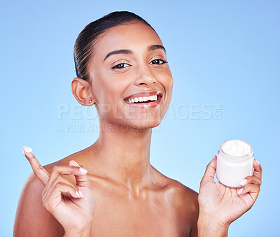 Buy stock photo Cream jar, portrait and woman in studio with facial product for aesthetic skincare, dermatology or smile on blue background. Happy indian model, face lotion and glow of cosmetics container for beauty