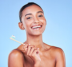 Portrait, woman and brushing teeth in studio for dental wellness, care and healthy smile on blue background. Happy indian model, bamboo toothbrush and cleaning mouth for oral hygiene of fresh breath 