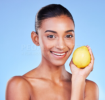 Buy stock photo Lemon, portrait and beauty of happy woman in studio for vitamin c benefits, eco cosmetics or nutrition. Face of indian model, healthy skincare and citrus fruit of vegan dermatology on blue background