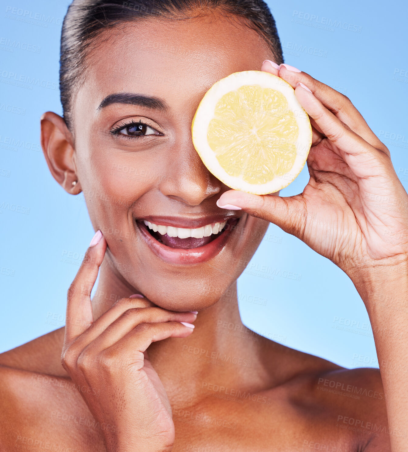 Buy stock photo Portrait, happy woman and lemon on eyes in studio for vitamin c cosmetics, natural beauty and detox. Face of indian model, healthy skincare and citrus fruit for vegan dermatology on blue background