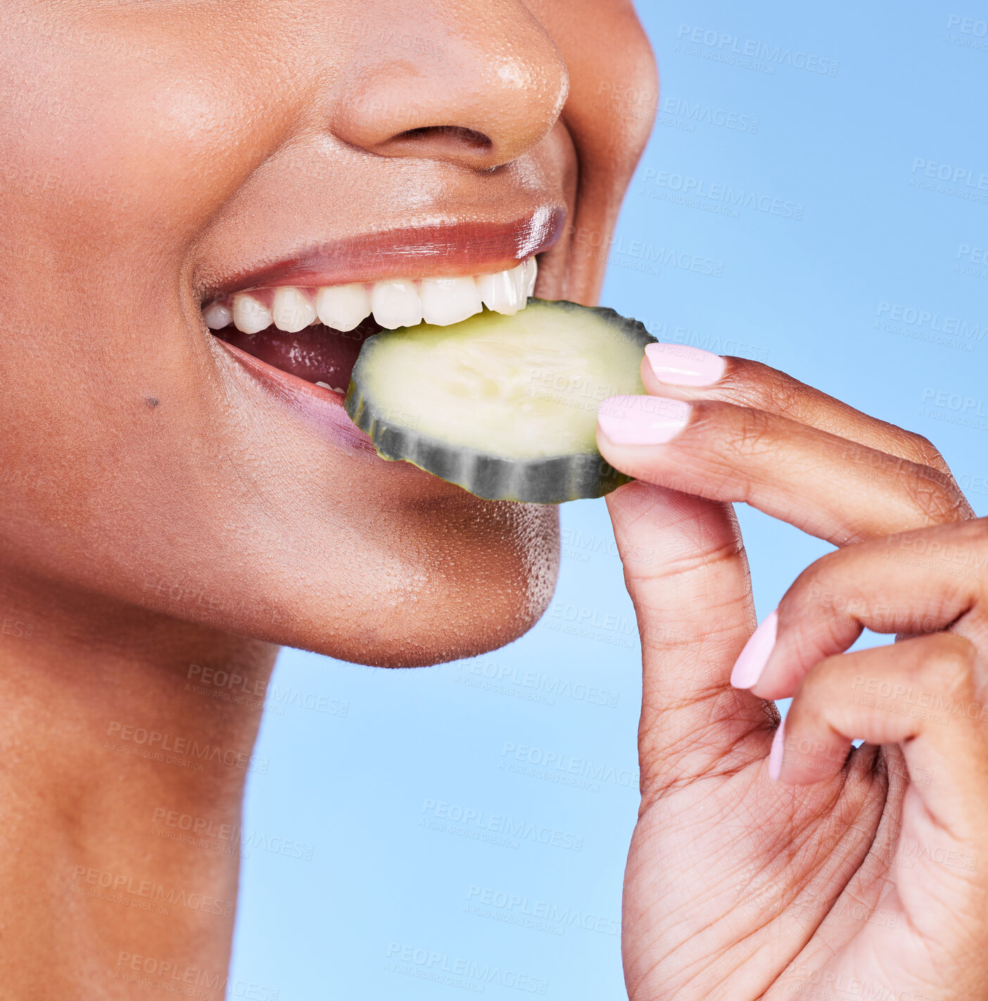 Buy stock photo Woman, mouth and bite on cucumber in diet, natural nutrition or detox against a blue studio background. Closeup of female person eating organic vegetable in healthy wellness, dermatology or beauty