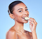 Happy woman, portrait and cucumber in diet, detox or natural nutrition in healthy wellness against a blue studio background. Female person eating organic vegetable in happiness, dermatology or beauty