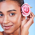 Rose, portrait and skincare of woman in studio for eco cosmetics, natural glow and aesthetic on blue background. Face, happy indian model and flowers for beauty, sustainability or floral dermatology 