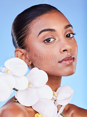 Buy stock photo Flower, skincare and portrait of woman in studio for beauty, wellness and organic body care on blue background. Floral, face and Indian female model with petals for eco friendly dermatology or shine