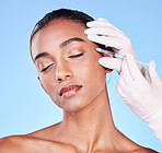 Needle, woman and face in studio for skincare, beauty process and aesthetic filler on blue background. Indian model, hands of surgeon and injection for plastic surgery, facial change or prp cosmetics