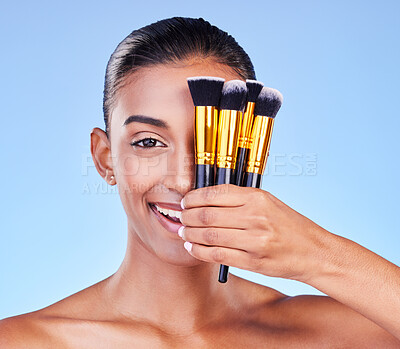 Buy stock photo Woman, portrait and beauty, makeup and brush for foundation with cosmetics isolated on blue background, Happy Indian model, wellness and cosmetology with tools or equipment, skin and shine in studio