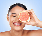 Portrait, health and grapefruit with a natural woman in studio on a blue background for beauty or wellness. Face, smile and aesthetic skin with a happy young model holding fruit for diet or detox