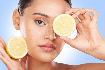 Buy stock photo Lemon, portrait and beauty of woman in studio for vitamin c cosmetics, natural diet and detox. Face of model, healthy skincare and citrus fruits on eyes for sustainable dermatology on blue background