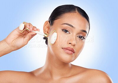 Buy stock photo Woman, face and roller, beauty and skincare with tools, stone and natural cosmetics on blue background. Facial massage, portrait and skin glow, crystal and equipment with dermatology in a studio