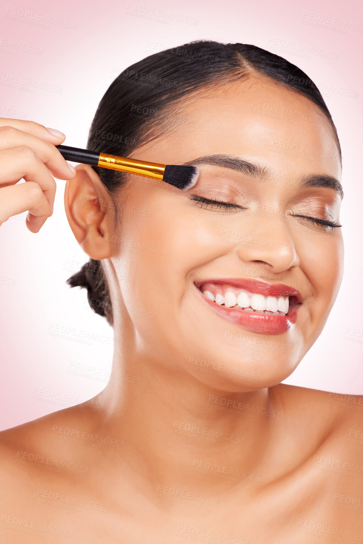 Buy stock photo Happy, eyeshadow and a woman with a brush on a pink background for skincare, wellness and health. Smile, young and a female model with makeup, beauty or foundation on face for cosmetics on a backdrop