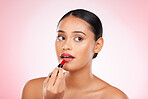 Red, lipstick and face of woman with makeup or cosmetics on pink background space and thinking about product. Lips, beauty and model with ideas for aesthetic skincare or choice of color on mouth 