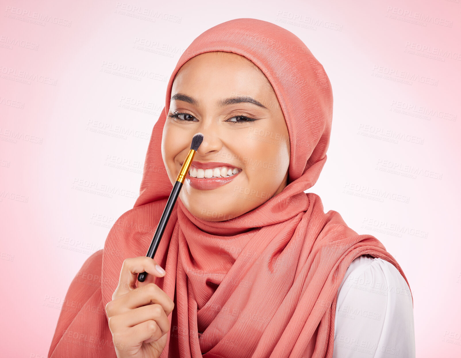 Buy stock photo Makeup brush, portrait and happy Muslim woman with studio cosmetics tools, anti aging glow or aesthetic skincare. Facial product application, smile and face of Islamic Arabic model on pink background