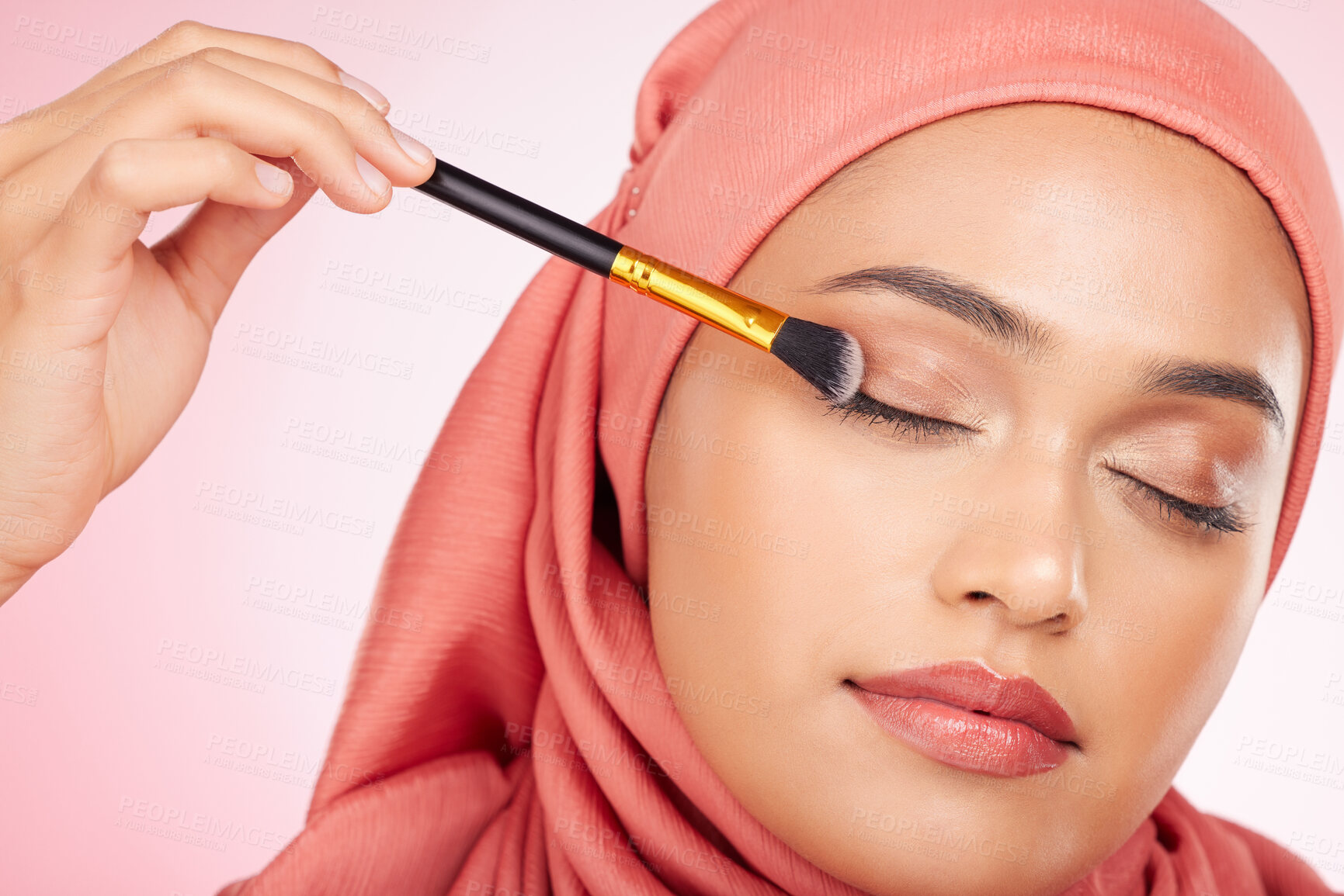 Buy stock photo Makeup, brush and muslim woman in studio with eyeshadow, application and wellness on pink background. Beauty, glamour and female model with hijab, cosmetics and luxury, makeover or transformation